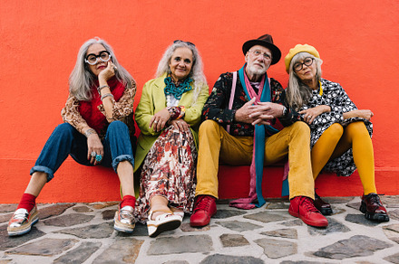 Carefree elderly friends sitting against a red wall, a Person Photo by Jacob Lund