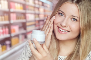 Happy woman applying facial cream on her cheek, smiling and test, a Person Photo by Studio ANNA