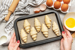 Baker holding baking tray with freshly made croissants, ready to, a Food & Drink Photo by Olena Rudo