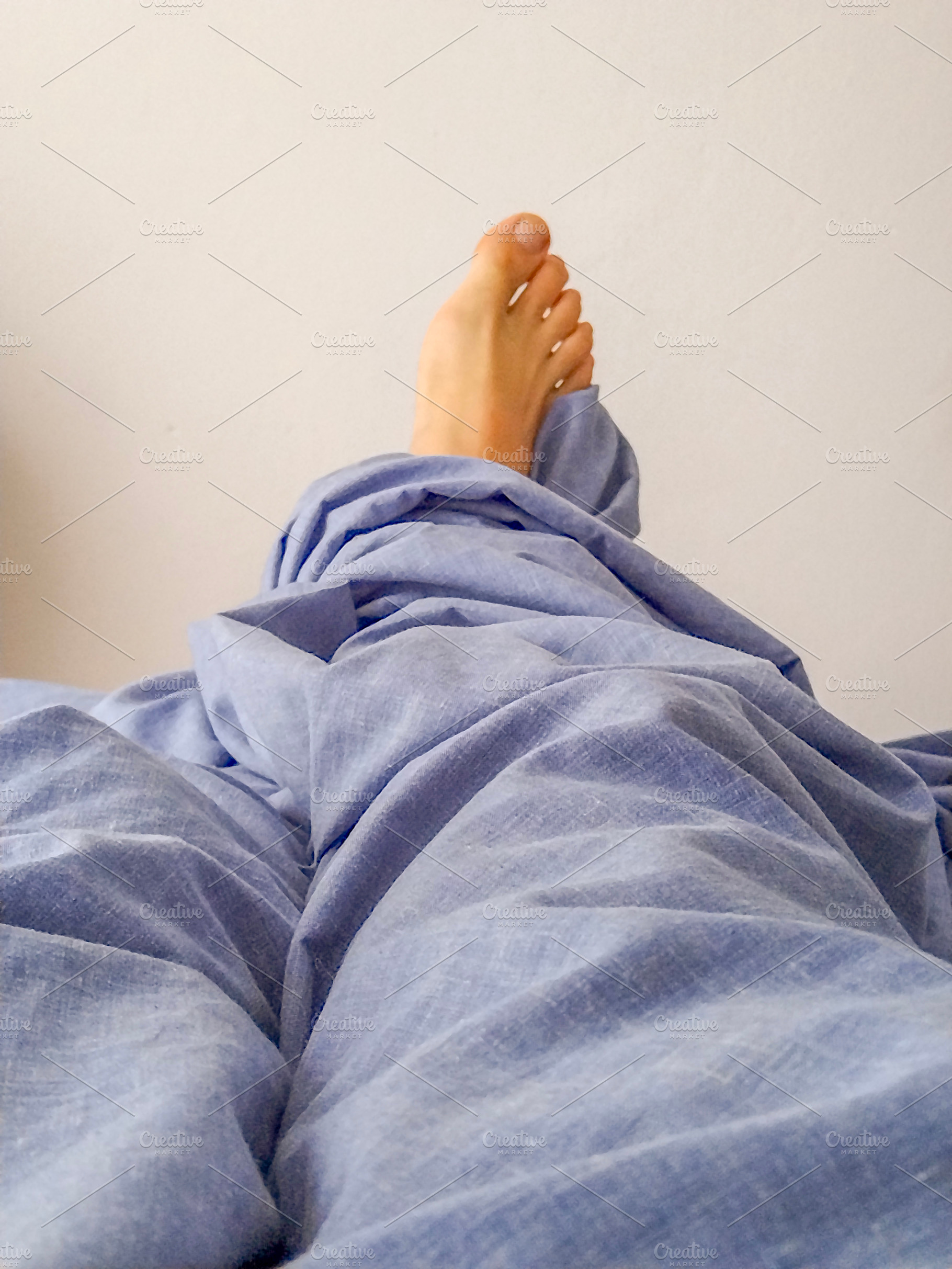 Feet under blanket in peaceful rest scene, a Health & Medical Photo by DanFLCreativo