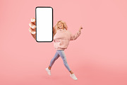 Happy young lady showing empty smartphone screen while jumping up over pink stu, a Photo by Prostock-Studio (Thumbnail 1 of 3)