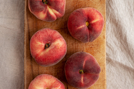 Organic Donut Saturn Peaches on a rustic wooden board, top view., a Food & Drink Photo by LiudmylaChuhunova