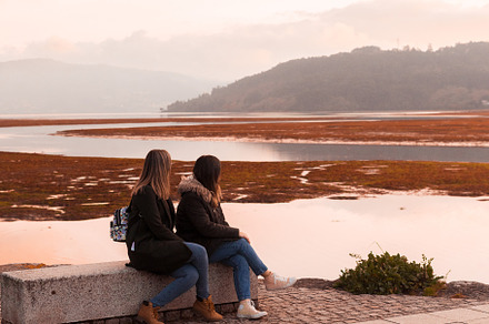 Two female friends sitting on a bench, a Person Photo by rubenchase