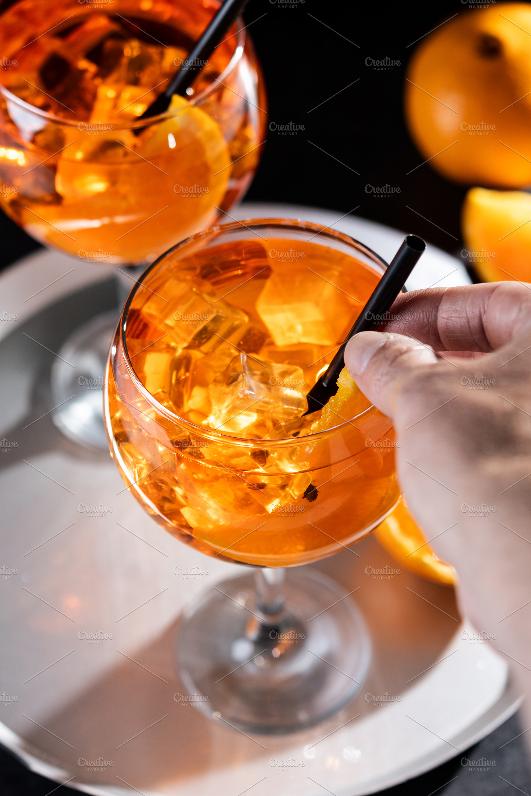 Hand holding Aperol Spritz cocktail with ice and orange slice, a Food & Drink Photo by etorres69
