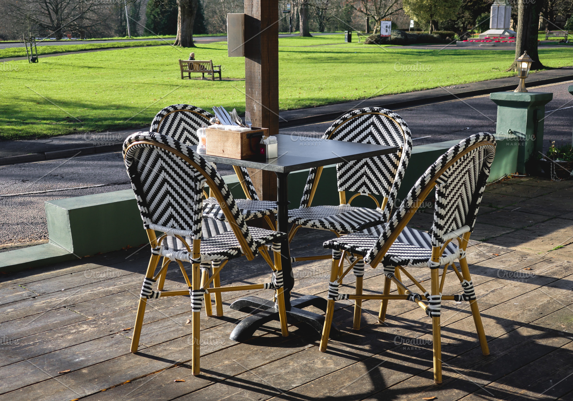 Empty outdoor cafe seating with bistro chairs on wooden deck ove, a Photo by Studio ANNA