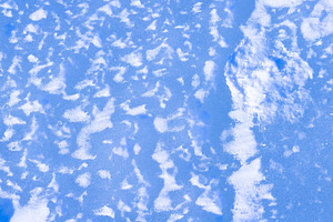 Natural blue ice with snow, rough frozen winter surface