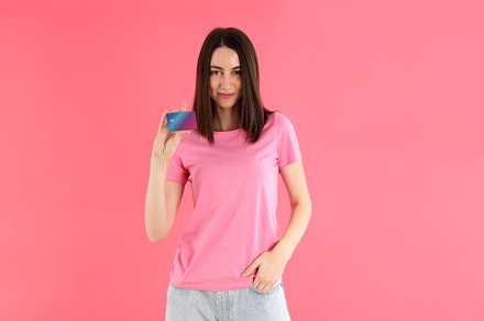 Attractive woman in t-shirt holds card on pink background, a Person Photo by AtlasStudio PRO