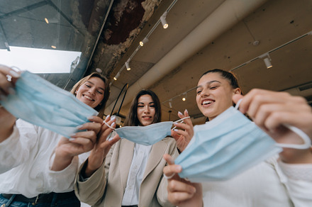 Caucasian women taking off a medical mask in a cafe