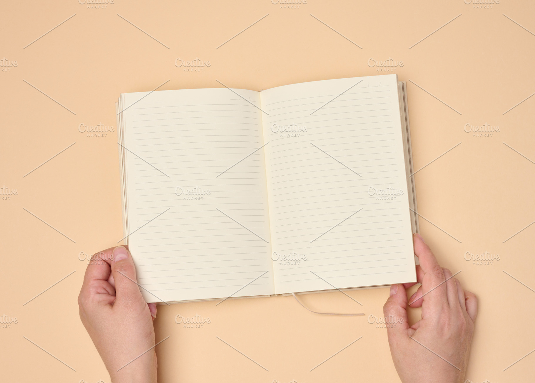 Hands hold a blank open notebook on a neutral background, an Abstract Photo by ndanko