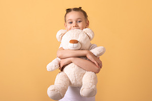 Smiling young girl in white t-shirt embraces plush teddy bear ag, a Person Photo by Ales Munt