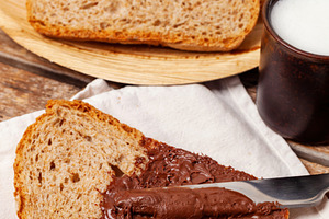 Spreading chocolate cream on a slice of whole wheat bread during breakfast, a Food & Drink Photo by Antonio Gravante Market