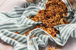 Granola pouring from jar on striped cloth, a Food & Drink Photo by Olena Rudo