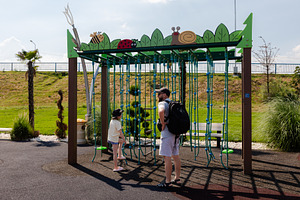 Man and young girl standing by a colorful rope climbing frame at an outdoor pla, a Person Photo by Ales Munt