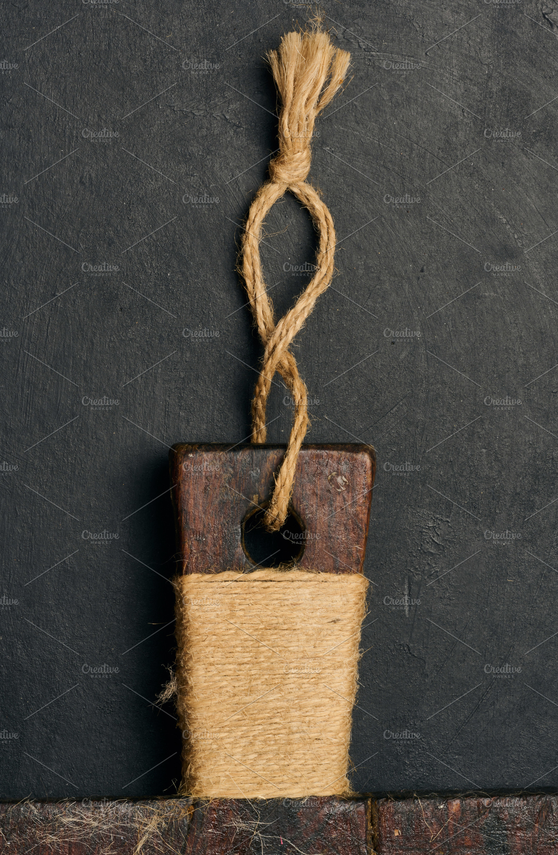 An old cutting board handle made of dark wood, wrapped in natura, a Food & Drink Photo by ndanko
