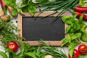 Fresh herbs and spices framing empty blackboard on gray backgrou, a Food & Drink Photo by Olena Rudo