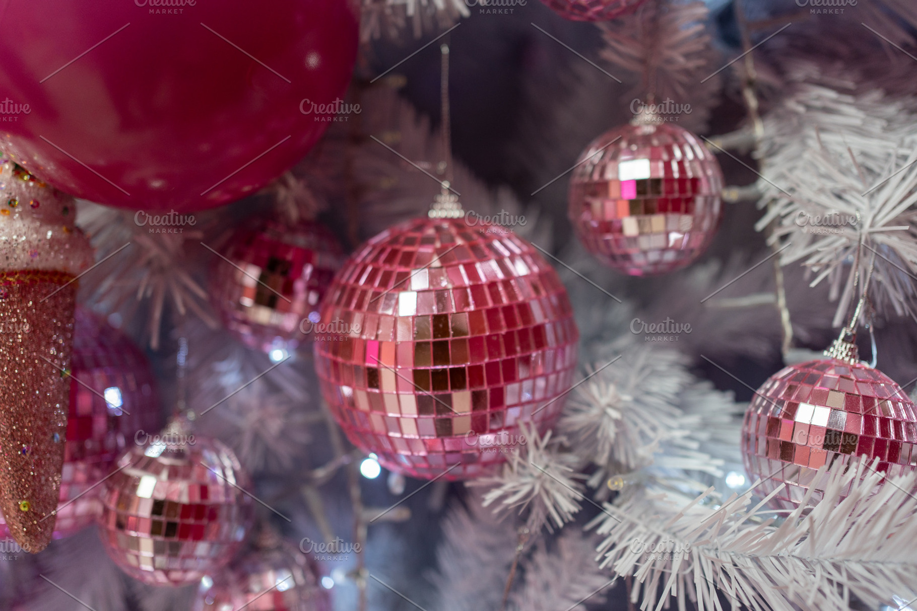 Closeup of shiny pink baubles hanging on illuminated Christmas tree, a Photo by andreonegin market