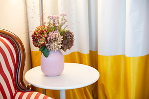 Flower arrangement in a pink vase on a white side table next to