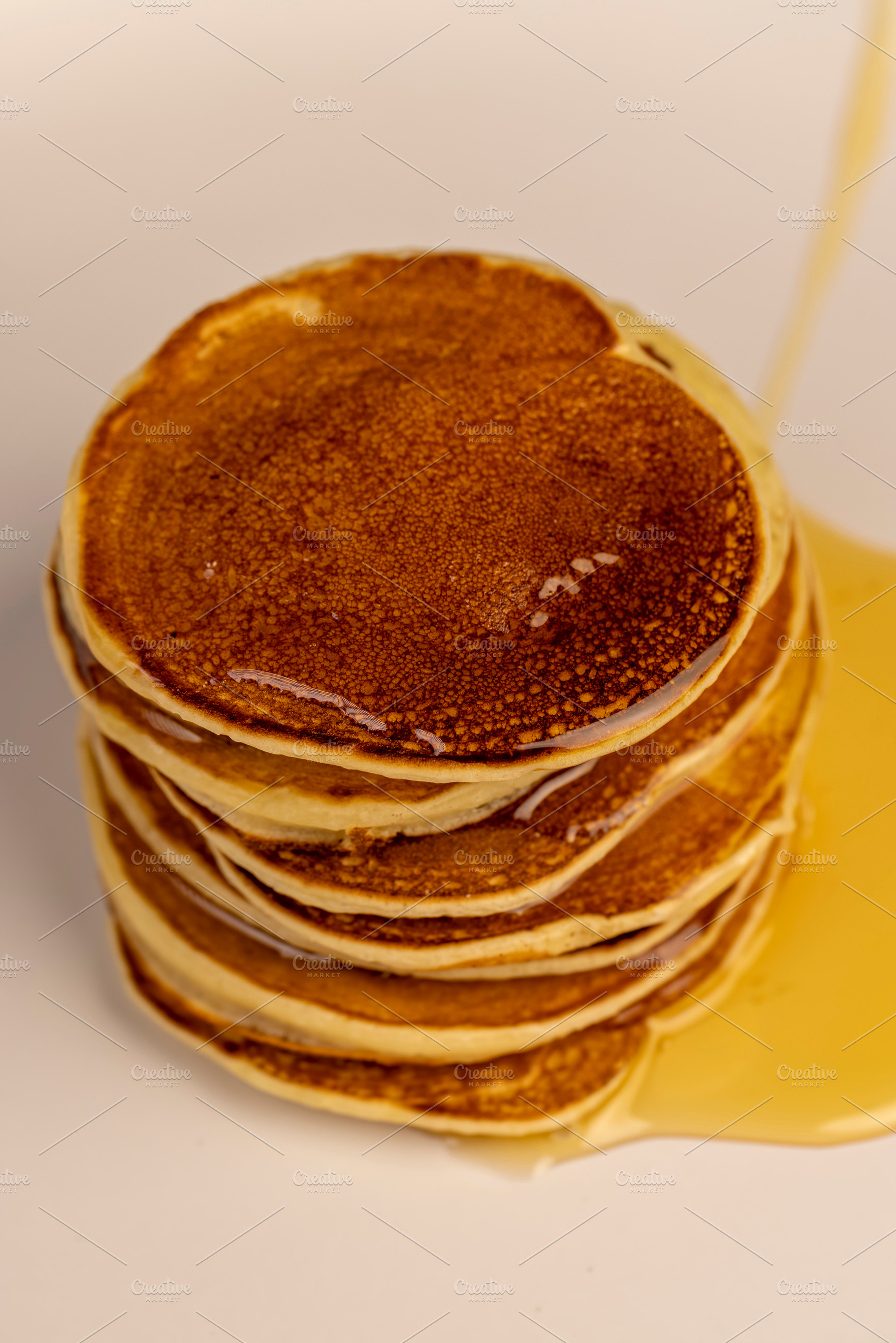 a tower of small milk pancakes on a ceramic bowl with natural yellow bee honey,, a Photo by rsoollAI