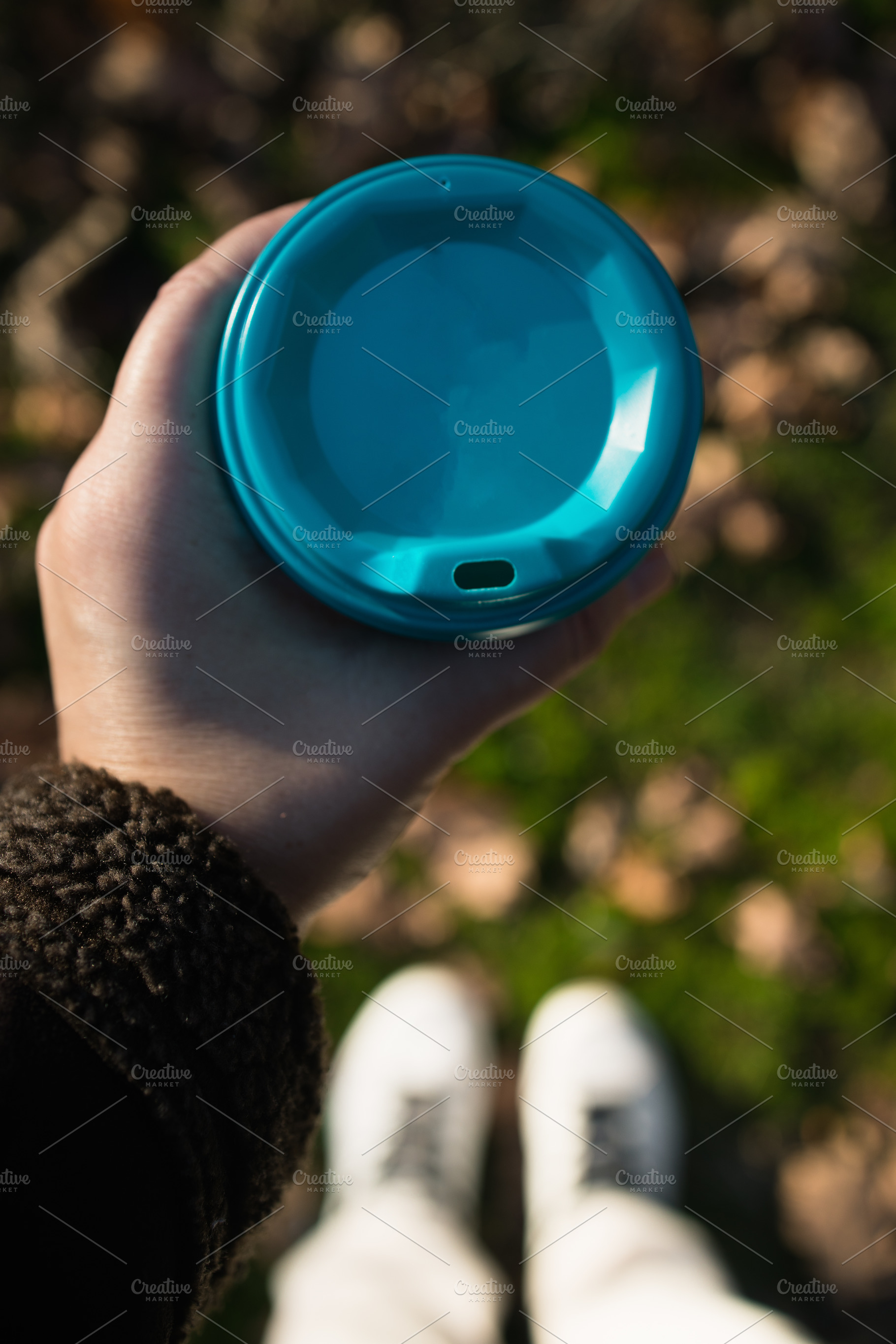 a glass with takeaway coffee in hands, against the background of blurry autumn, a Food & Drink Photo by TanaCh