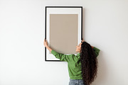 Woman Hanging Frame With Empty Poster On White Wall Indoors, a Photo by Prostock-Studio (Thumbnail 1 of 2)
