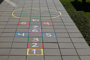 Colorful hopscotch game on pavement in Akranes, Iceland under sunlight, a Photo by AS photostudio