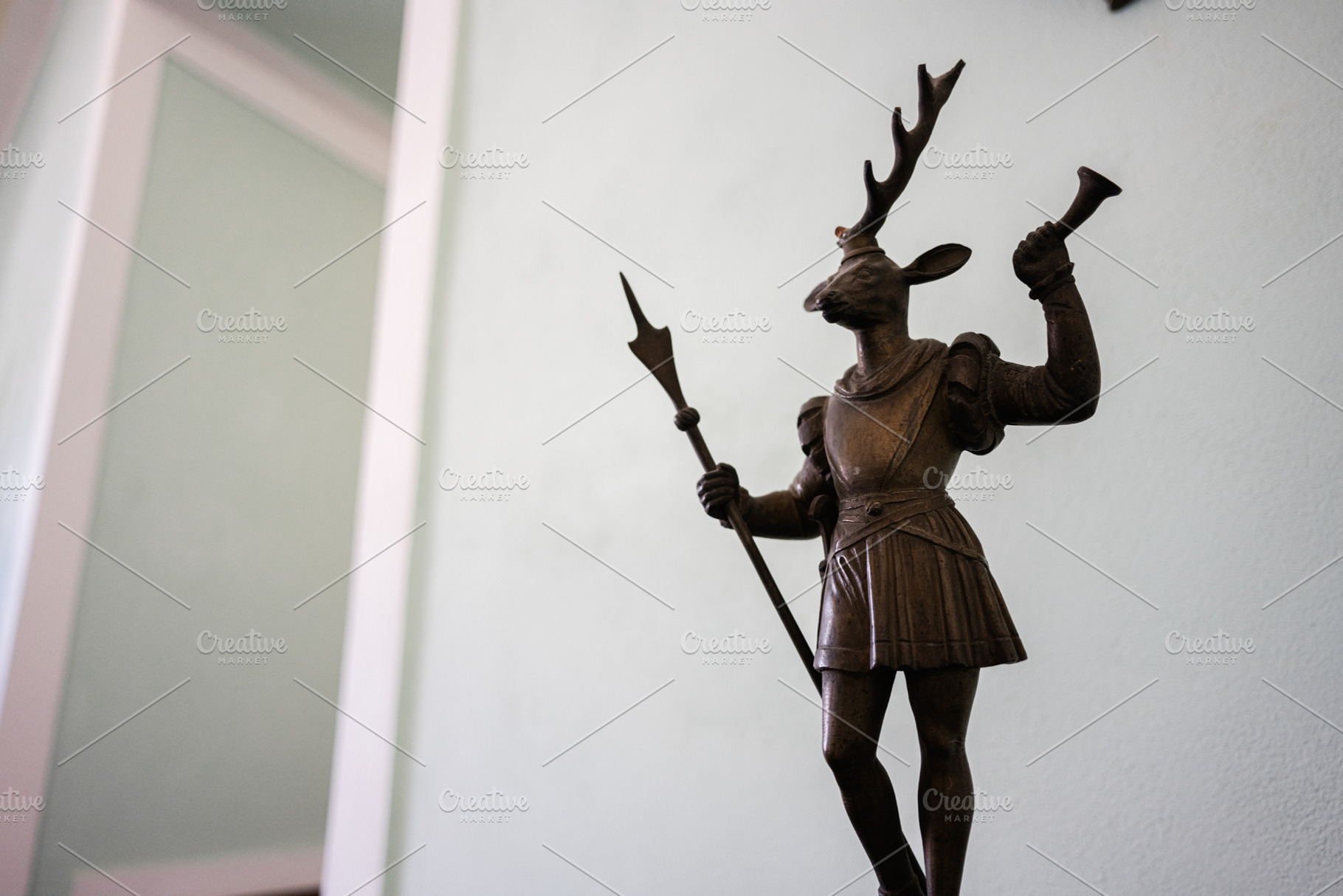 Sculpture of a deer-headed knight holding a trumpet and spear indoors, a Photo by AS photostudio