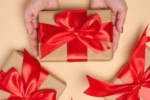 A woman's hands in a white sweater hold a gift box wrapped in cr, a Holiday Photo by ndanko