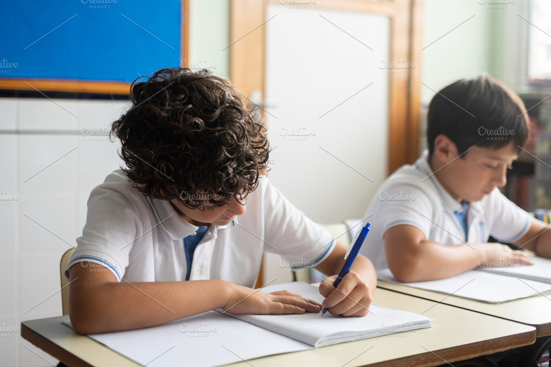 Elementary school boys writing in notebooks during a classroom lesson, a Person Photo by etorres69