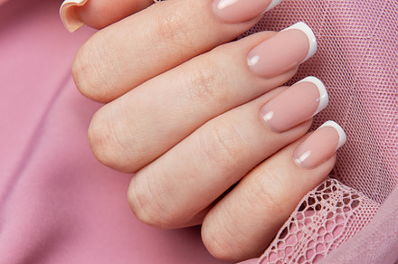 Woman showing french manicure on pink background with lace