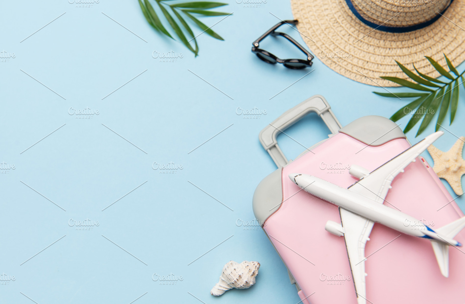 Pink suitcase with toy airplane, sunglasses, straw hat, seashell, a Holiday Photo by Olena Rudo