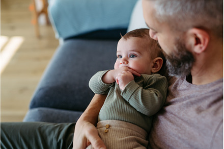Father holding baby boy in arms, a Person Photo by HalfPoint