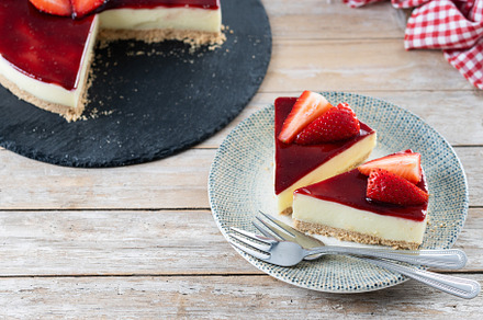 Slice of cheesecake with strawberries on wooden table, a Food & Drink Photo by etorres69