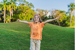 Boy wearing a pilot hat running, a Nature Photo by Elizaveta Galitskaya