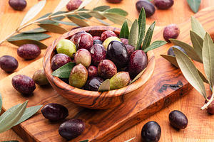 Fresh olives in wooden bowl on the wood background., a Food & Drink Photo by Volff