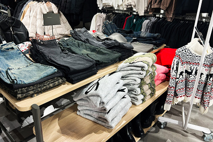 Folded clothes and jackets organized in a retail clothing store, a Photo by AS photostudio