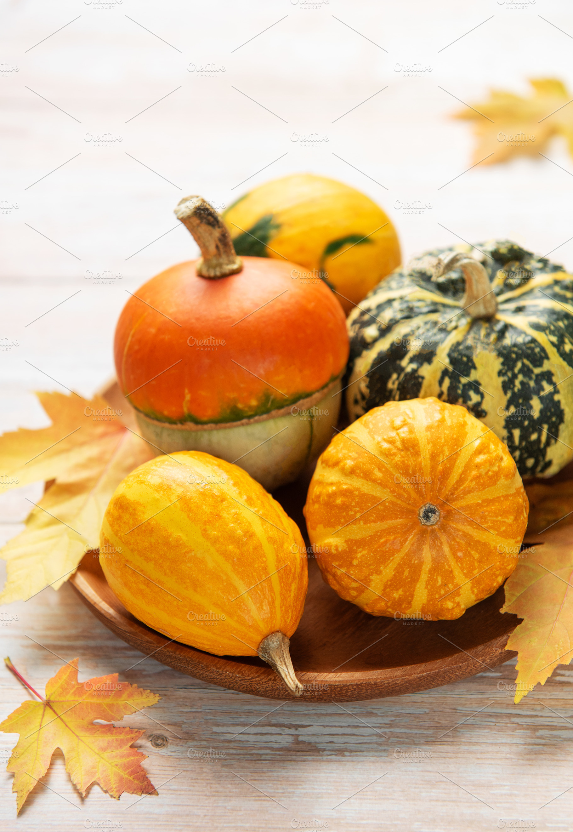 Decorative gourds pumpkins and autumn leaves on wooden tray, a Food & Drink Photo by Olena Rudo