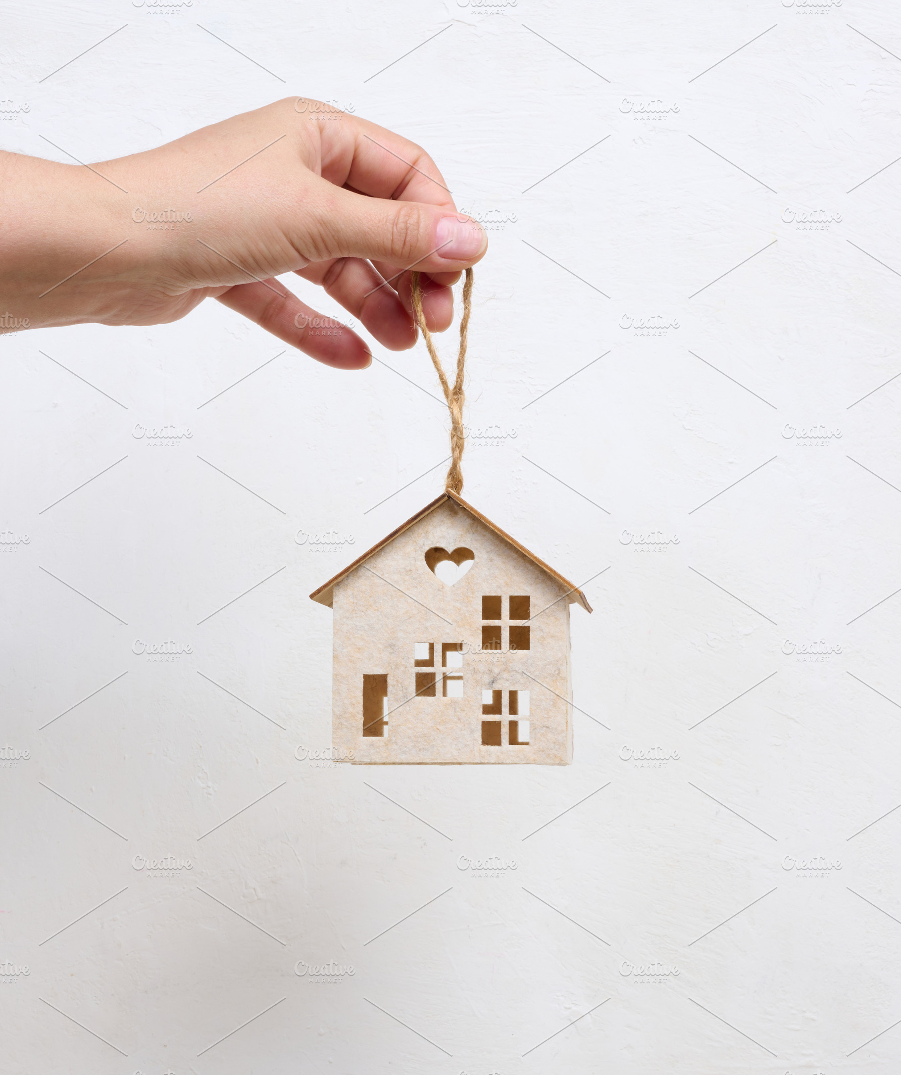 Person holding a small wooden house model on their palm against, a Business Photo by ndanko