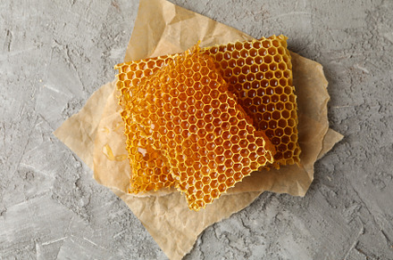 Baking paper with honeycomb pieces on gray background, a Food & Drink Photo by AtlasStudio