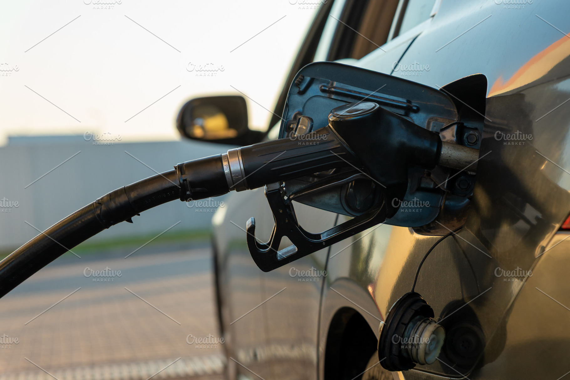 Close-up of a fuel nozzle refilling a car at a gas station, captured in natural, a Transportation Photo by Ales Munt