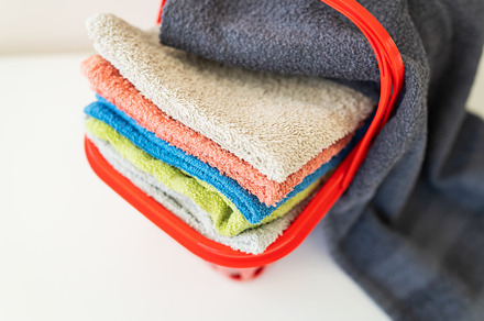 Multi-colored towels lie in a red laundry basket on a white background. Washing, a Beauty & Fashion Photo by Artsaba Family
