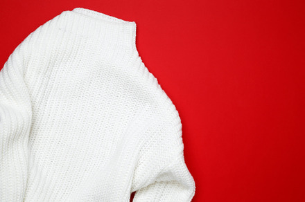 White sweater displayed on a red background, simple and stylish fashion item, a Photo by matucha