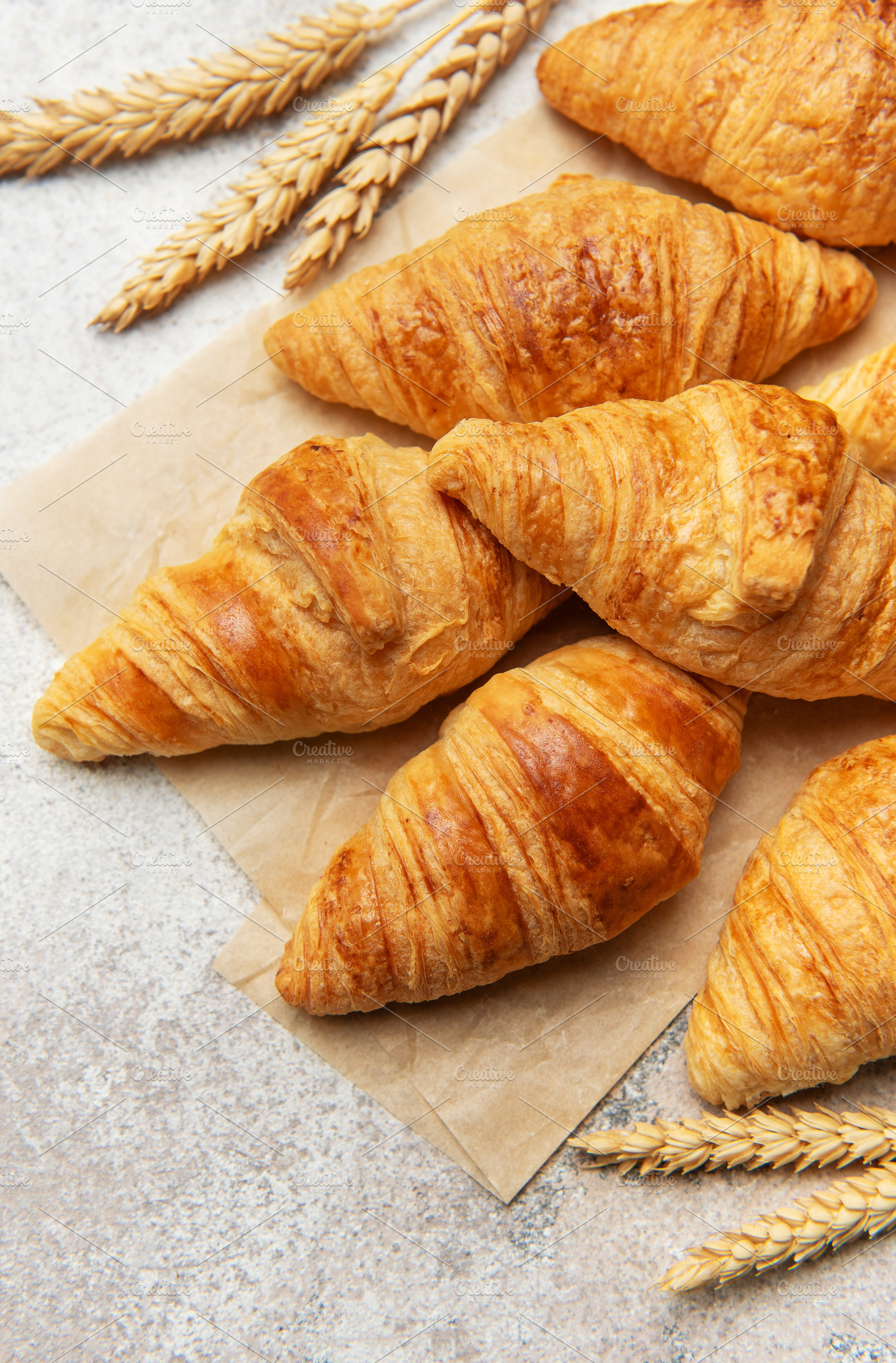 Freshly baked croissants with wheat on baking paper, a Food & Drink Photo by Olena Rudo