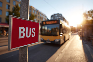 A city bus approaching a bus stop during golden hour, casting a warm glow on th, a Person Photo by ImageMir