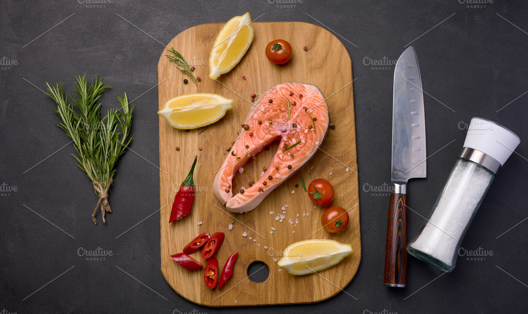 Raw salmon steak on a wooden cutting board, lemon slices, spices, a Food & Drink Photo by ndanko
