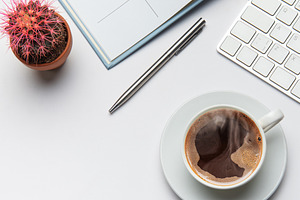Office worker desk with coffee, cactus, pen, eyeglasses, and key, a Business Photo by Olena Rudo