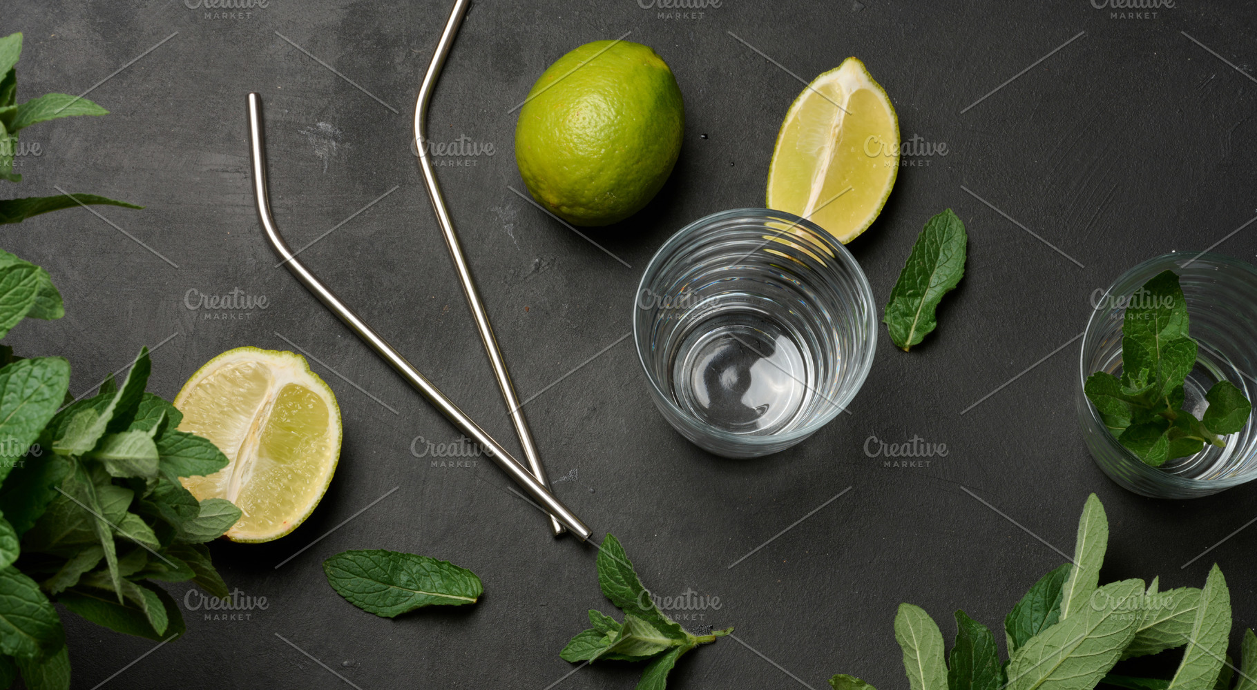 Bunch of fresh green mint, lime slices, glasses and metal straws, a Food & Drink Photo by ndanko