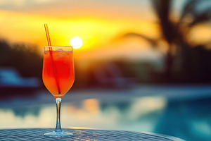 Refreshing glass of vibrant fruit cocktail against a stunning sunset backdrop, a Food & Drink Photo by AlyaAnd
