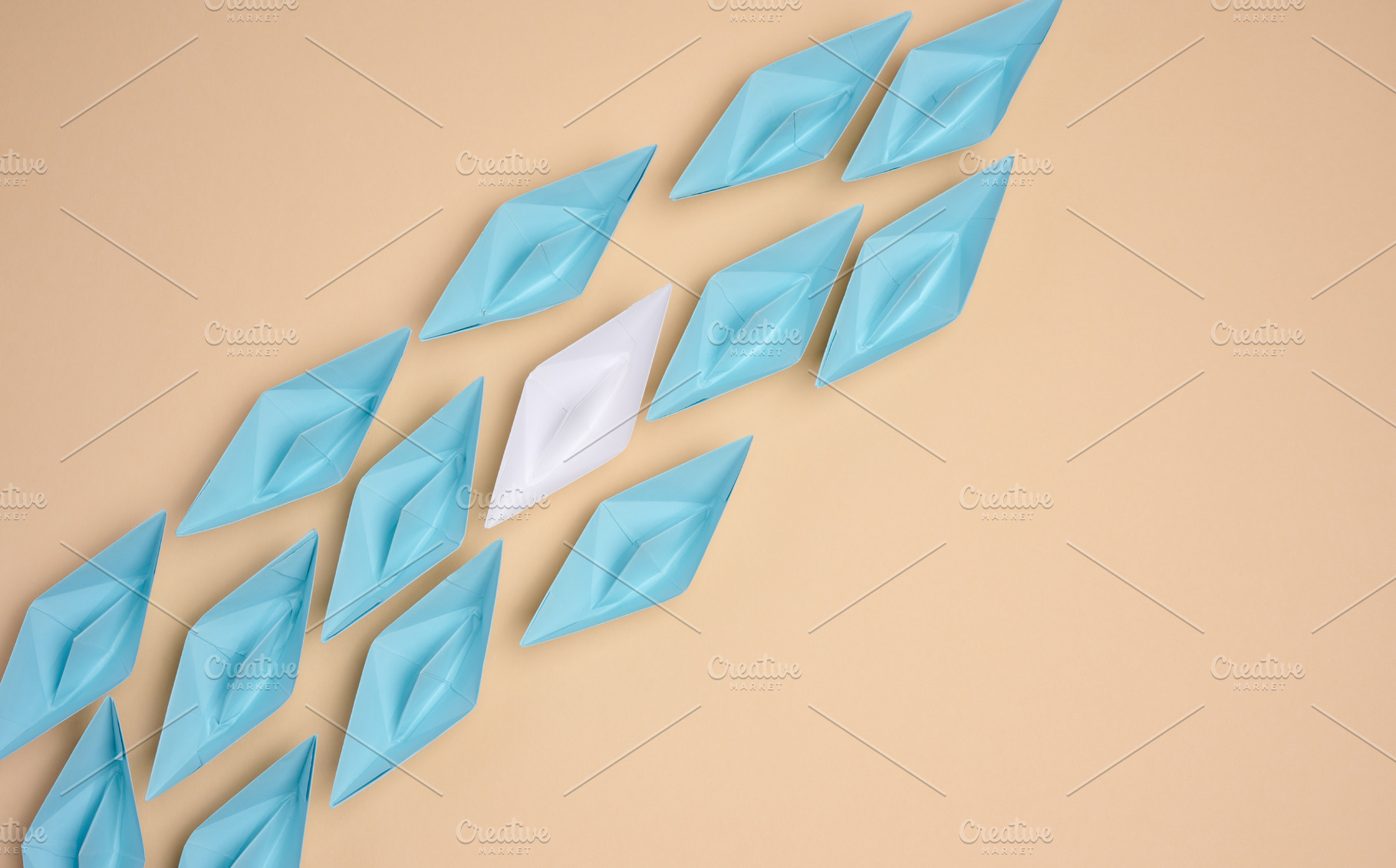 A white origami paper boat stands apart from a group of blue one, a Business Photo by ndanko