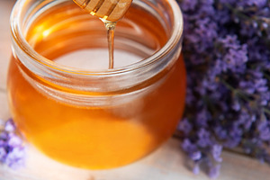 Golden honey dripping from dipper with lavender flowers, a Food & Drink Photo by Olena Rudo