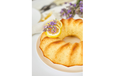Round lemon cake on white table with, a Food & Drink Photo by IlliaBondarPhotography